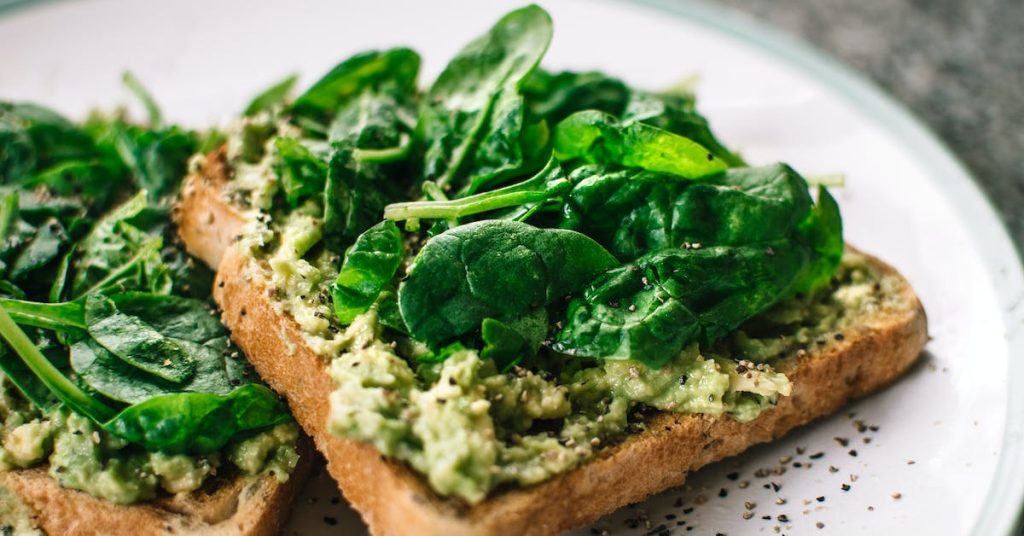 basil-leaves-and-avocado toast-on-sliced-bread-on-white-ceramic-plate