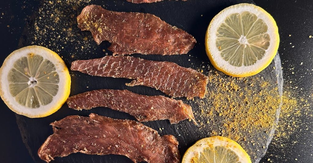 strips-of-meat-sprinkled-with-turmeric-powder-and-served-with-slices-of-lemon